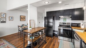 A modern kitchen with dark cabinets, stainless steel appliances, and a wooden dining table. - Romantic getaway with a view; close to SDC and the Branson Strip (Branson West)