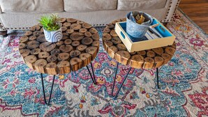 Two round coffee tables with wooden logs as tops, a potted plant, and a metal container with books and a blue object on a patterned rug. - Romantic getaway with a view; close to SDC and the Branson Strip (Branson West)