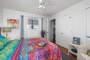 A bedroom with a bed, a ceiling fan, a window with curtains, a fan, a door, and a wicker chair. - Romantic getaway with a view; close to SDC and the Branson Strip (Branson West)