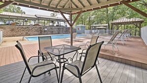 An outdoor pool area with a covered patio, lounge chairs, and a table with chairs. - Romantic getaway with a view; close to SDC and the Branson Strip (Branson West)