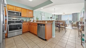 A spacious kitchen with modern appliances, a dining area with a view, and a cozy living space. - Upscale Refined Unit, Oceanfront Water Amenities | Crescent Shores - N 1304 (North Myrtle Beach)