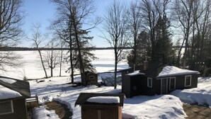 A residential area with snow-covered ground, a small wooden shed, and a house with a chimney. - Where eagles soar, the sun sets low and the deer are friendly.  (Saint Germain)