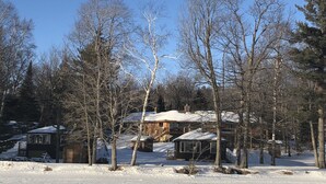 A snow-covered landscape with several cabins surrounded by trees. - Where eagles soar, the sun sets low and the deer are friendly.  (Saint Germain)