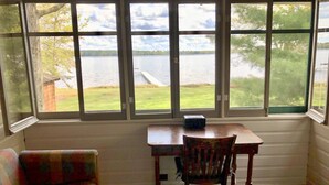 A room with a view of a lake, a wooden desk, a chair, and a sofa. - Where eagles soar, the sun sets low and the deer are friendly.  (Saint Germain)