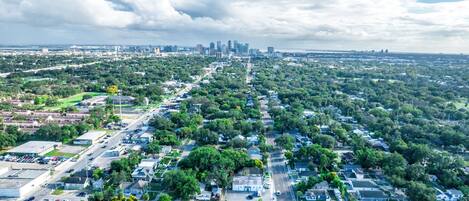 An aerial view of a residential area with houses, streets, and a distant city skyline.