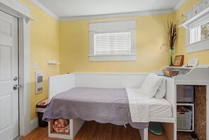 A small, single-bed room with a window, a radiator, and a door. - Inn The Heights - Tiny House  (Tampa)