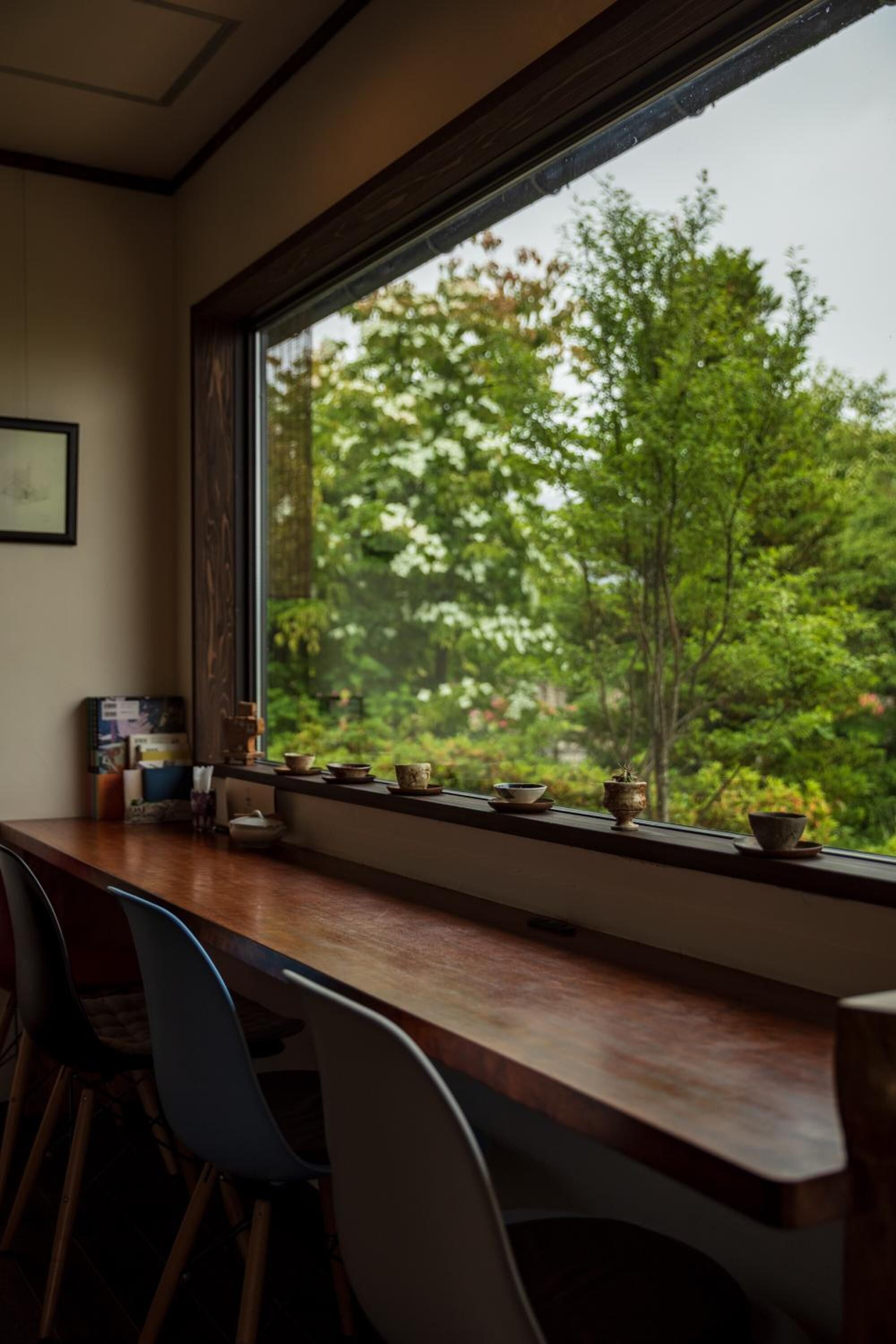 A wooden table with chairs and a window overlooking a forest.