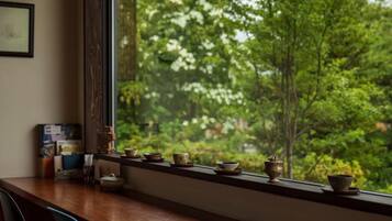A wooden table with chairs and a window overlooking a forest.