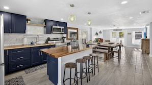 Una cocina moderna con armarios azul oscuro, una isla de madera y taburetes de bar.