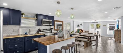A modern kitchen with dark blue cabinets, a wooden island, and bar stools.