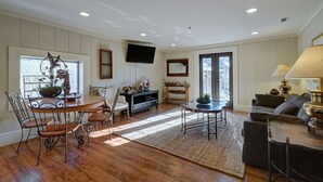 Un vaste espace de vie comprenant une table à manger en bois, des chaises, un canapé et un téléviseur fixé au mur.