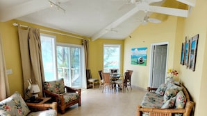 A spacious living room with a dining area, large windows, and a ceiling fan. - ONE OF A KIND PROPERTY! Breathtaking Views, Ocean Breezes, Huge Dock, Peaceful (Georgetown)
