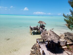 A wooden pier with a thatched roof seating area and a small table, overlooking clear turquoise waters. - Snorkel off the backyard pier! Breathtaking Views, Ocean Breezes, Tranquil (Georgetown)