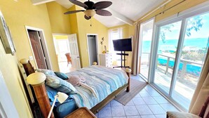 A bedroom with a bed, a ceiling fan, a TV, and a view of the ocean. - ONE OF A KIND PROPERTY! Breathtaking Views, Ocean Breezes, Huge Dock, Peaceful (Georgetown)