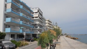 Una hilera de edificios de varios pisos con balcones, un paseo pavimentado y una masa de agua al fondo.