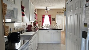A kitchen with white cabinets, a black countertop, and a tiled floor. - Family‑Friendly Ocean‑View Home • 4BR/3BA • Steps to Beach • Sleeps 8‑10 (Myrtle Beach)