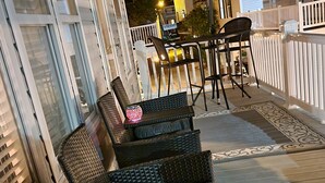 A patio with wicker furniture, a table, and chairs, and a decorative lantern. - Family‑Friendly Ocean‑View Home • 4BR/3BA • Steps to Beach • Sleeps 8‑10 (Myrtle Beach)