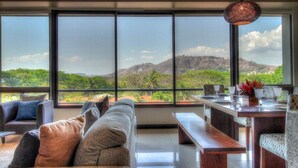 A modern living room with a large window overlooking a mountainous landscape. - Condo w/ rooftop terrace & ocean views (Playa Hermosa,)
