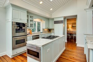 A kitchen with light blue cabinets, stainless steel appliances, and a large island.