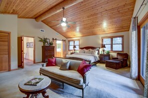 A bedroom with a wooden ceiling, a bed, a sofa, a nightstand, and a chair.