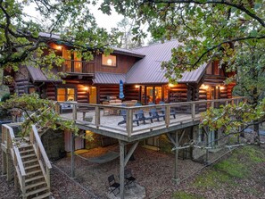 A log cabin with a deck, outdoor seating, and a staircase leading to the entrance.