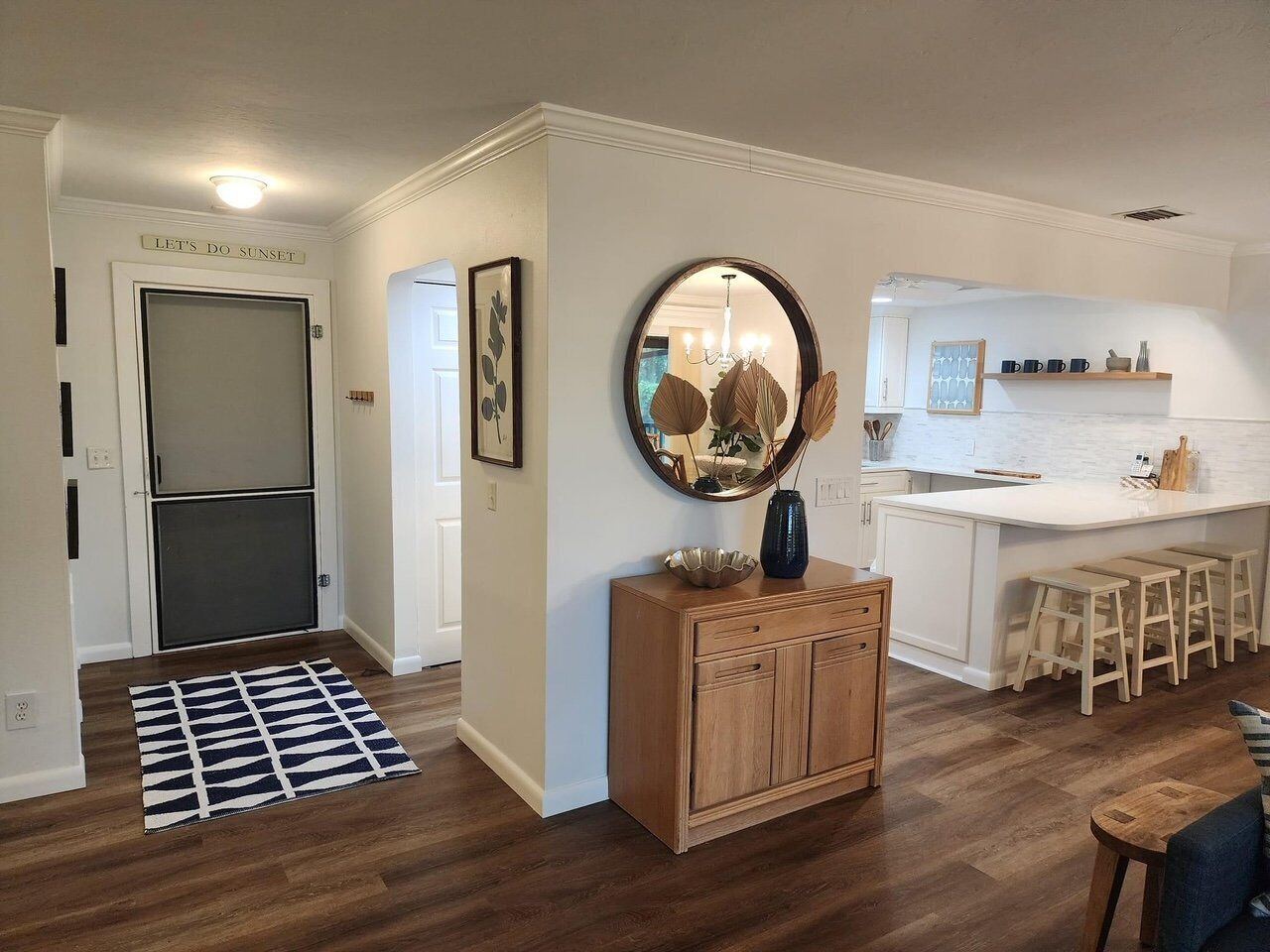 A modern kitchen with a central island, wooden cabinets, and a dining area with stools.