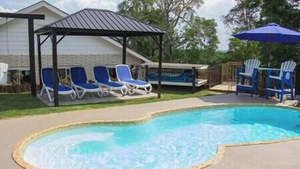 A swimming pool with a curved edge, surrounded by blue lounge chairs.
