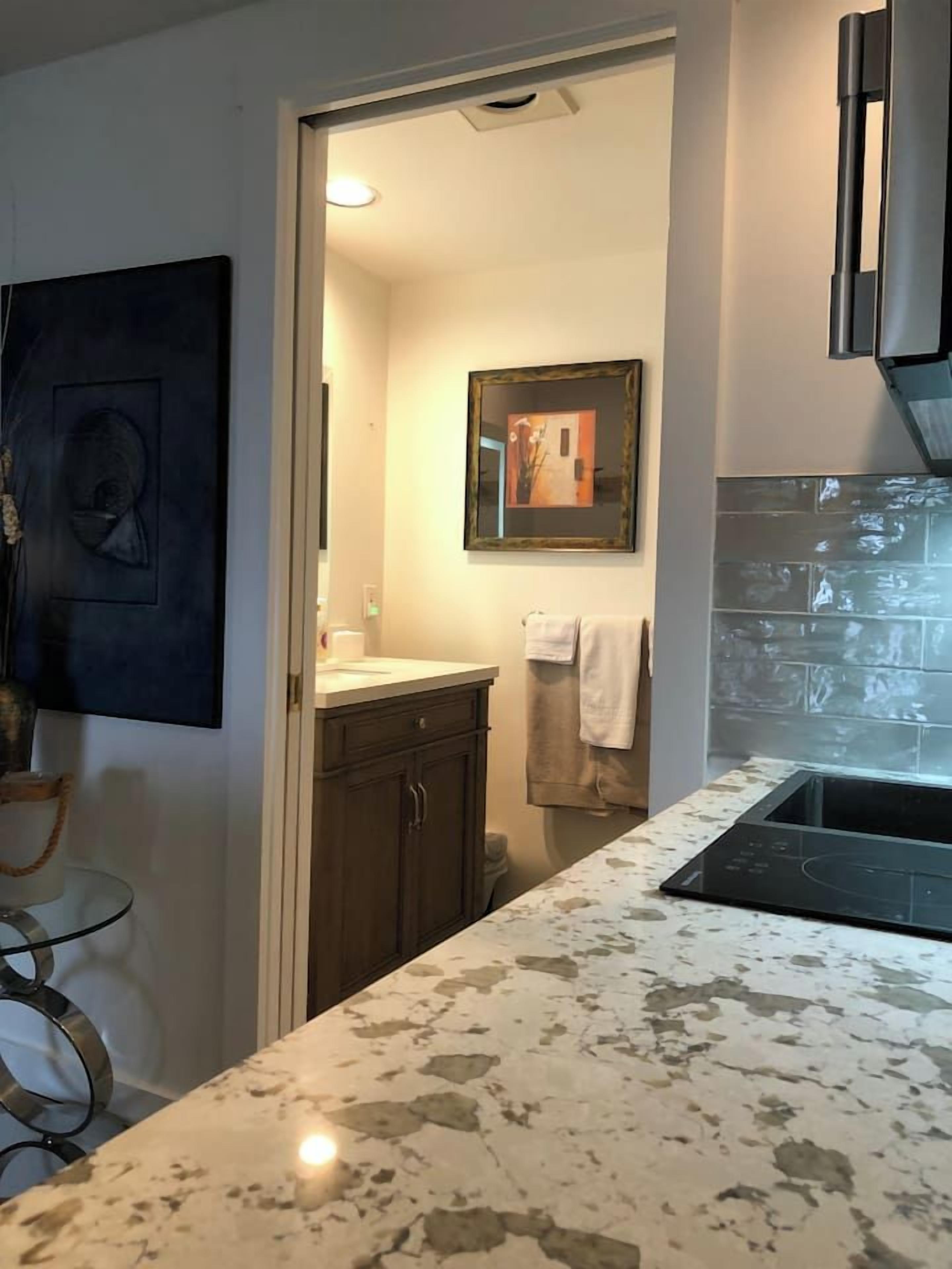 A modern kitchen with a marble countertop, dark cabinets, and a tiled backsplash.