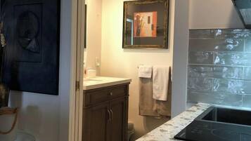 A modern kitchen with a marble countertop, dark cabinets, and a tiled backsplash.