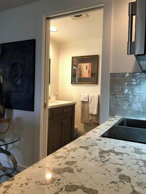 Una cocina moderna con encimera de mármol, armarios oscuros y salpicadero de azulejos.