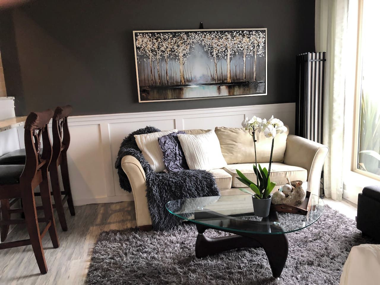 A living room with a sofa, coffee table, and a painting on the wall.
