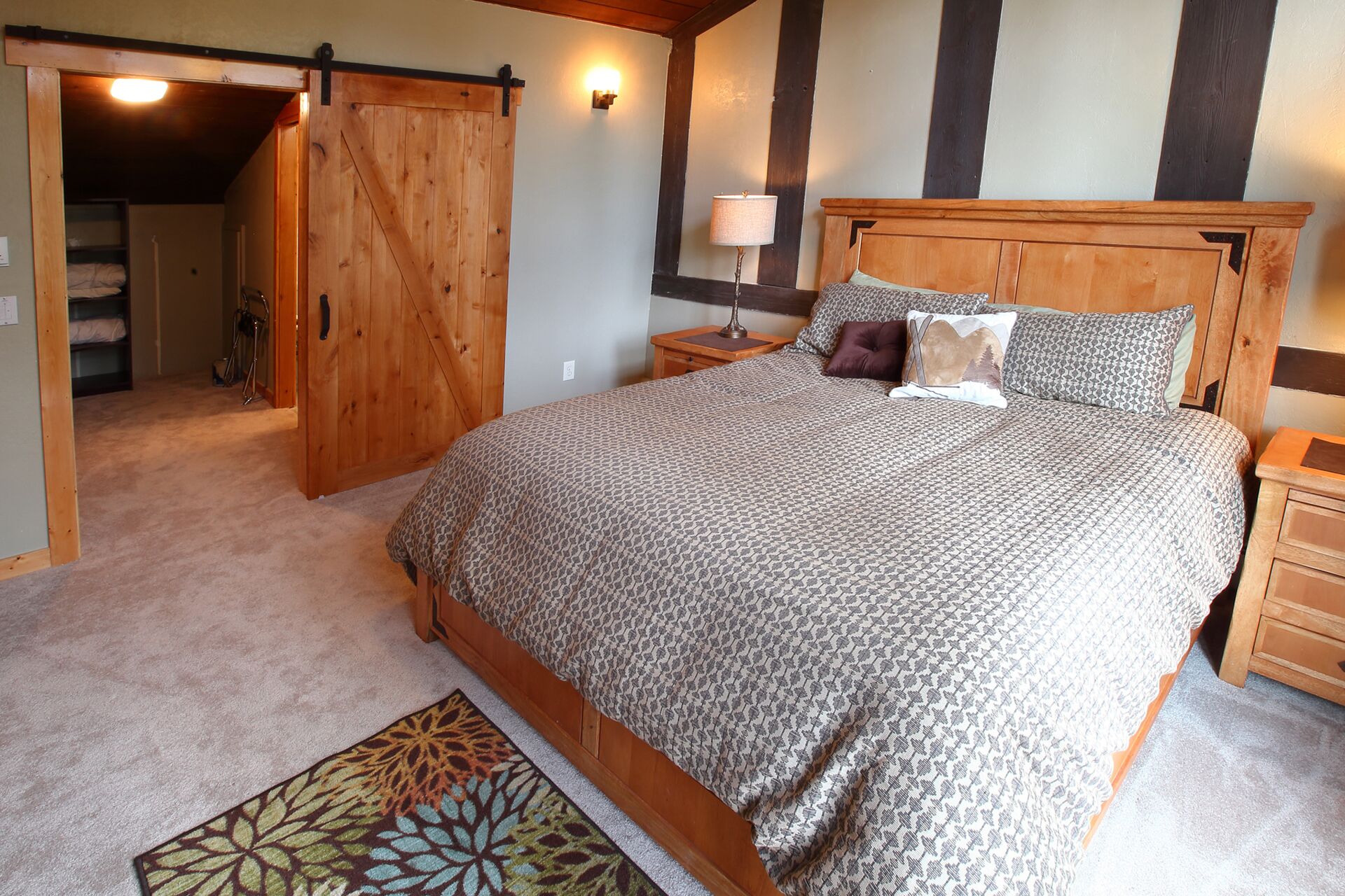 A bedroom with a large bed, a wooden headboard, a nightstand, a lamp, and a door leading to a closet.