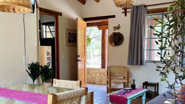 A spacious room with a tiled floor, wooden furniture, and a large window with curtains.