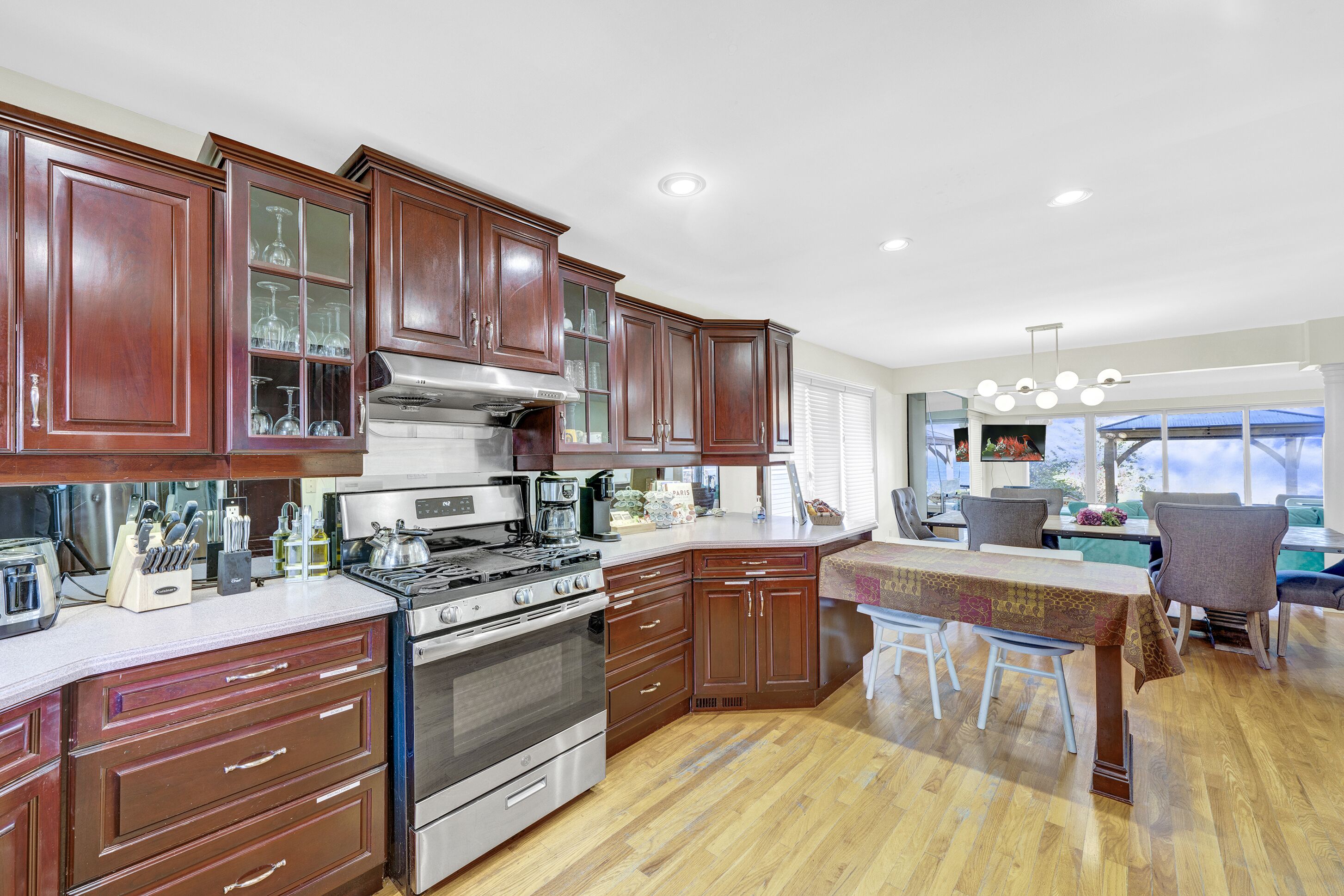 A modern kitchen with wooden cabinets, stainless steel appliances, and a dining area with a table and chairs.