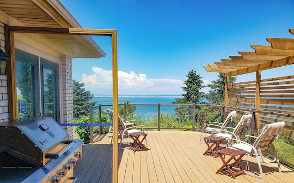 An upper deck with a BBQ and views of the ocean.
