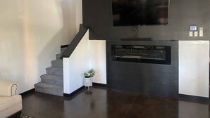 A modern living room with a staircase, a flat-screen TV mounted on a dark wall, and a built-in entertainment unit. - New Waterfront Flowage to Full Rec Lake Home On UTV Sled Trails Sleeps 10 (Mountain)