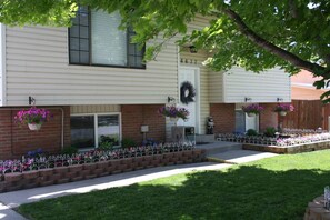 A two-story house with a front porch, a brick entrance, and a mailbox. - 4BR Sleeps 12, Games, Private Yard and Fire Table (West Jordan)