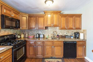 Cocina con armarios de madera, estufa, microondas y lavavajillas.