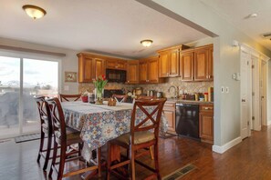 A kitchen with wooden cabinets, a dining table with chairs, and a view through a sliding glass door.
