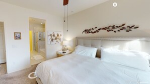 Habitación de hotel con una cama grande, un cabecero con diseño de hojas, una mesita de noche con lámpara y un espejo.