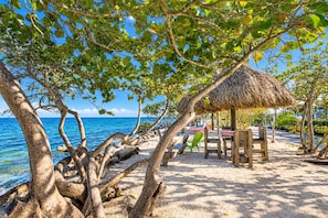 A beach scene with a thatched-roof hut, wooden furniture, and a view of the ocean. - Beautiful Updated Kawama Townhouse.  Marina, boat ramp, lagoon and pools. (Key Largo)
