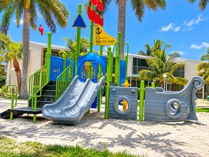 A playground with a slide, climbing structures, and a sign indicating a pirate ship theme. - Beautiful Updated Kawama Townhouse. Marina, boat ramp, lagoon and pools. (Key Largo)
