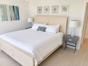 A bedroom with a bed, two bedside tables with lamps, a nightstand, and a wall with framed artwork. - Beautiful Updated Kawama Townhouse. Marina, boat ramp, lagoon and pools. (Key Largo)
