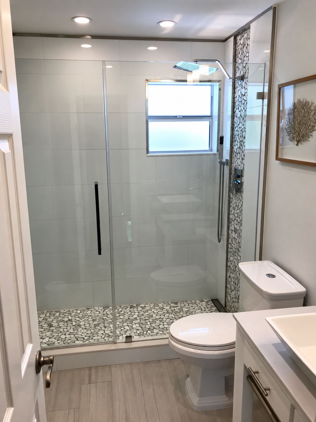 A modern bathroom with a glass-enclosed shower, a toilet, and a sink.