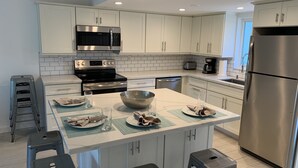 A modern kitchen with white cabinets, stainless steel appliances, and a central island with stools. - Beautiful Updated Kawama Townhouse.  Marina, boat ramp, lagoon and pools. (Key Largo)
