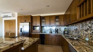 A kitchen with wooden cabinets, granite countertops, a stainless steel refrigerator, and a dishwasher. - Spectacular View and Luxury Condo - Pet Friendly - Weekly & Monthly discounts  (Cabo San Lucas)