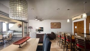 A modern living room with a dining area, a sofa, a TV, and a ceiling fan. - Spectacular View and Luxury Condo - Pet Friendly - Weekly & Monthly discounts  (Cabo San Lucas)