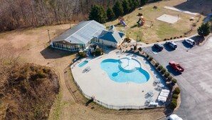 Vista aérea de una propiedad con piscina, un patio cubierto y un parque infantil.
