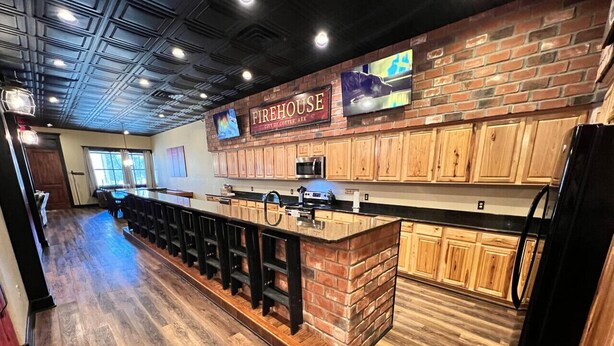 A bar area with a brick counter, wooden cabinets, and a sign that reads "Firehouse". - Historic FireHouse Lodge Very Cool! (COTTER)