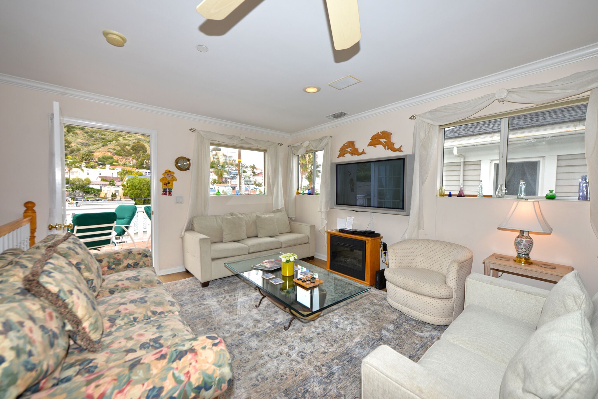 A living room with a glass coffee table, a sofa, a chair, and a television.